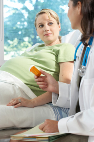 Side profile of a female doctor giving a bottle of pills to a pregnant woman